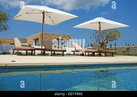 Menorca, Balearic Islands: lawn, pool, olive trees, deckchairs and beach umbrellas in the menorcan countryside Stock Photo