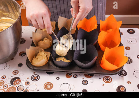 Womans Hands making delicious homemade Cupcakes, filling the forms Stock Photo