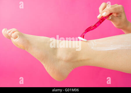 woman shaving her leg alone with red shaver Stock Photo