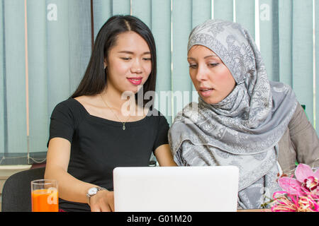 Asian and muslim girls working together on a laptop Stock Photo