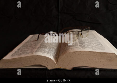 English dictionary with a pair of glasses resting on it. Stock Photo