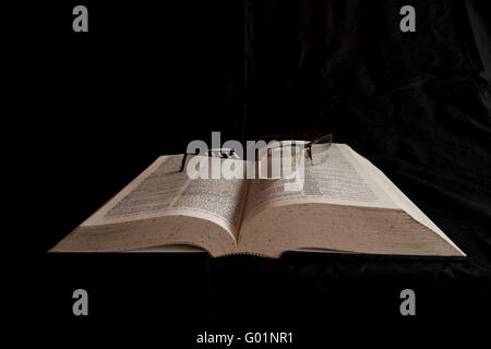English dictionary with a pair of glasses resting on it. Stock Photo