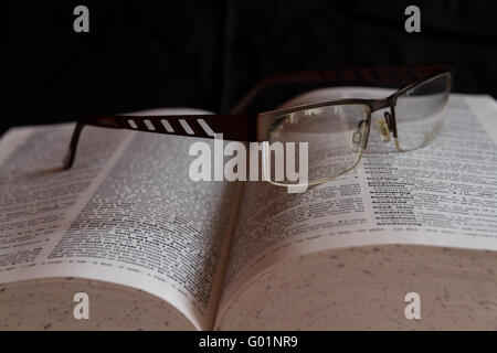 English dictionary with a pair of glasses resting on it. Stock Photo