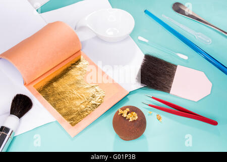 Pralines decorate gold platter gold gilt exquisite tweezers brushes hairpin leaf gold expensive exclusive chocolate Belgian Stock Photo