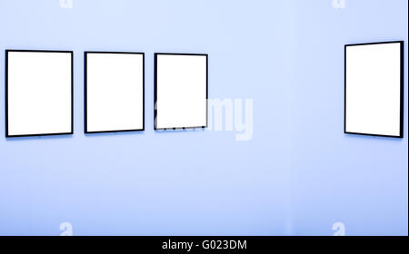 Four white empty frames on blue wall exhibition in Museum Stock Photo