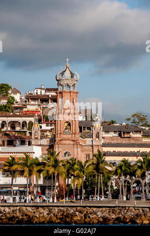 Our Lady of Guadalupe church and the old town Malecon of Puerto Vallarta seen from the water, with people walking the malecon Stock Photo