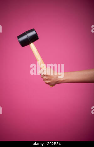 female hand holding hammer on pink background Stock Photo