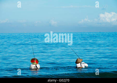 Two Balinese fishermen in the sea fishing. Stock Photo