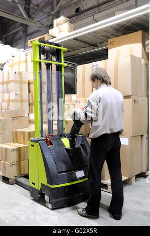 Operator of electric forklift stacker in warehouse Stock Photo