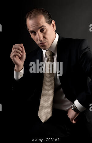 adult businessman well-dressed serious sitting looking at camera. Stock Photo