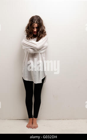 Young insane woman with straitjacket standing looking at camera Stock Photo