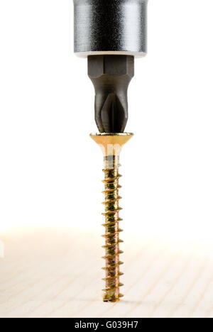 Closeup image of screwdriver and single screw in board on white background. Stock Photo