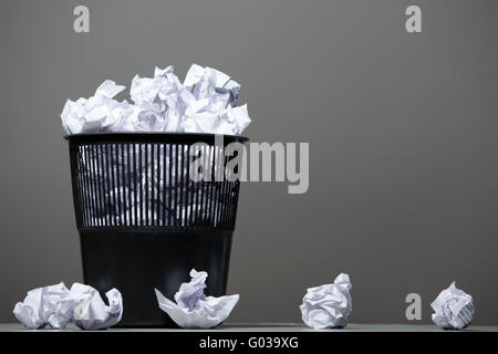 Recycle bin filled with crumpled papers. Gray background Stock Photo
