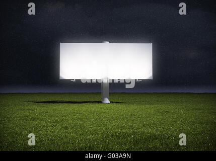 Ad billboard standing in a field of grass - night version Stock Photo