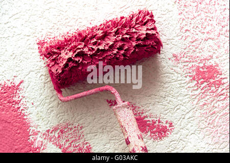 Paint roller with the color pink on a white wall Stock Photo