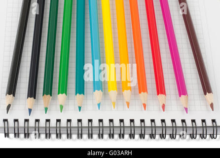 Multicolored pencils on opened spiral notebook Stock Photo