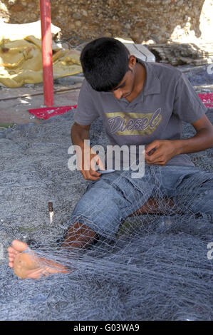 Young man mending the fishing nets, Sur, Oman Stock Photo