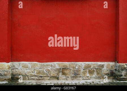 Red plastered house wall and stone base Stock Photo