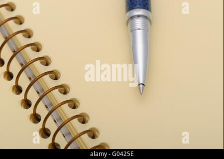 Pen and a notebook on a spiral with a yellow paper Stock Photo