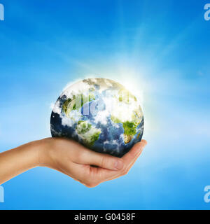 hand holding globe over blue sky - elements of this image furnished by NASA Stock Photo