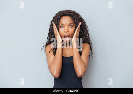 Amazed afro american woman looking at camera over gray background Stock Photo