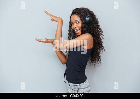 Happy afro american woman in headphones posing over gray background Stock Photo