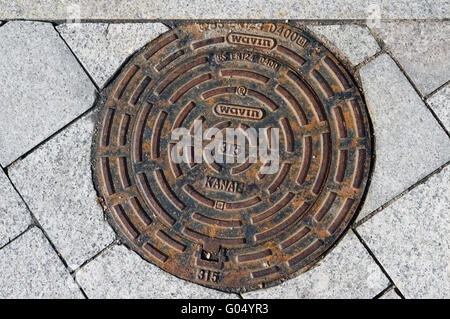 VILNIUS. LITHUANIA - MARCH 13, 2016: Pig iron hatch of the sewerage of the Danish firm Wavin on a granite pavement near national Stock Photo