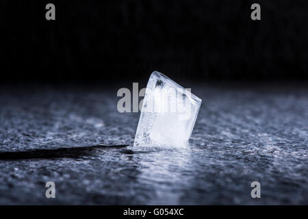 Melting ice cube in close up. Concept of cold temperature, water and change. Stock Photo