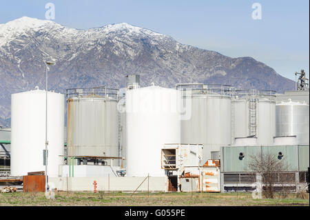 Tanks of a chemical plant at the foot of the mountains. Stock Photo