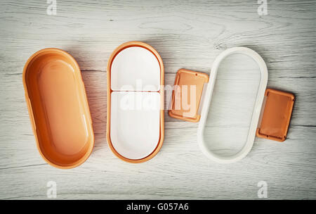 Orange folding plastic box for food storage on the wooden background. View from above. Open box. Kitchen equipment. Stock Photo
