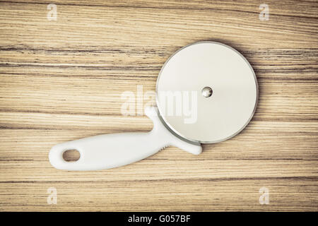 Pizza cutter on the wooden background. Kitchen equipment. Pizza slicer. Kitchen tool. Stock Photo