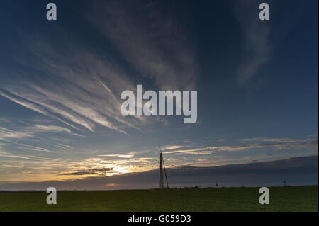 Mast of a wind turbine stands alone on the horizon Stock Photo