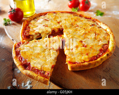 Cooked whole cheese and tomato Margherita pizza with a cut slice Stock Photo