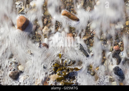 Flowing sea water at the beach pebbles on the shor Stock Photo