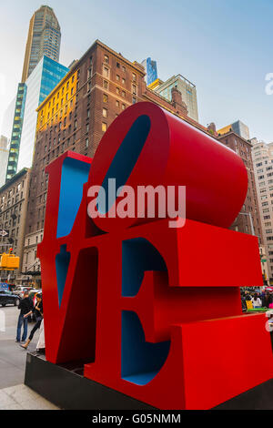 NEW YORK, USA - MAY 06, 2015: Love sculpture by American artist Robert Indiana and tourists passing by in Midtown Manhattan in New York, USA. The famous monument is located on 6th Avenue. Stock Photo