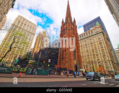 New York, USA - April 24, 2015: Street with tourists and traffic and Trinity Church in Manhattan, New York, USA. It is a historic parish church near Wall Street and Broadway. Stock Photo