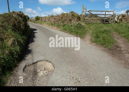 Countryside potholes in the road cause damage to cars and are a danger to unsuspecting motorcyclists and cyclists Stock Photo