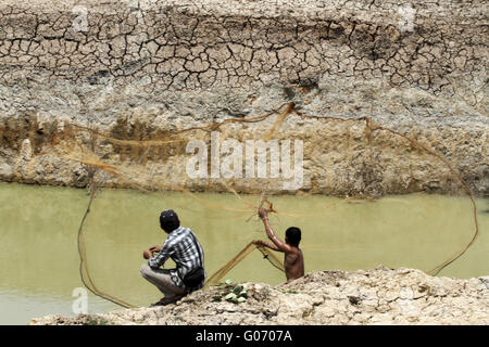 Local young kids fishing casting a net in a pond in the