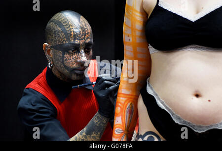 Brighton UK 30th April 2016 - This tattoo artist's head is totally covered with art as he works with a customer  at the 9th Annual Brighton Tattoo Convention held in the Brighton Centre this weekend  Credit:  Simon Dack/Alamy Live News Stock Photo