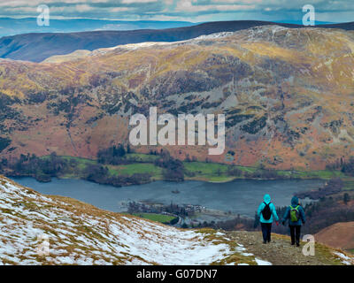 Winter hikers walking from the summit of Helvellyn towards Ullswater in the Lake District National Park Cumbria England UK Stock Photo