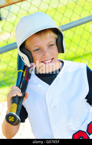 Cute baseball player in dugout Stock Photo