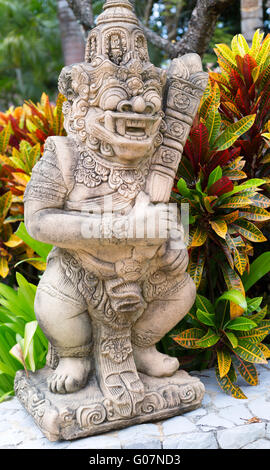 Thai stone god in the bushes of tropical plants Stock Photo
