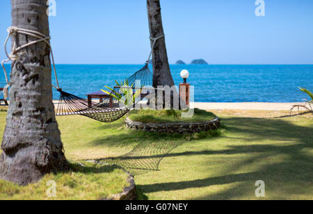 Hammock strung between two palms on tropical island. Stock Photo