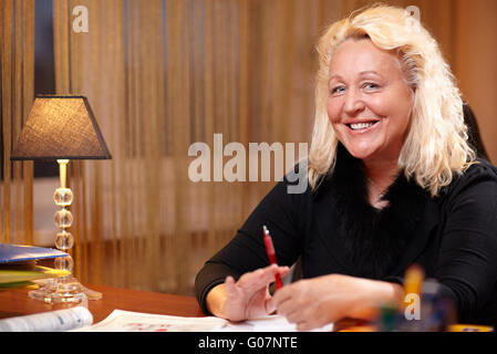 English teacher sitting at the table and smiling to the camera. Stock Photo