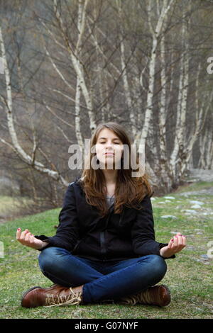 Young beautiful girl sitting on the grass and medi Stock Photo