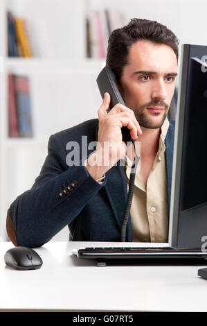 Man Looking At A Computer Monitor, on the phone Stock Photo