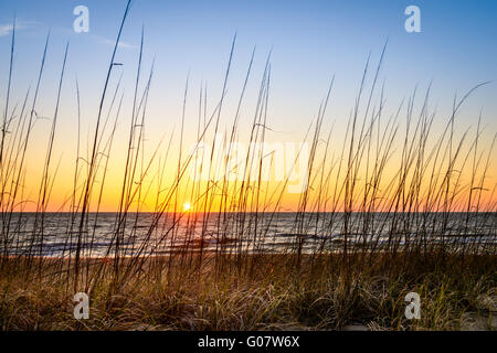 An image of a beautiful sunrise looking over a fence on the beach. Captured in Virginia Beach, Virginia. Stock Photo