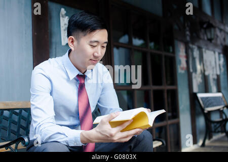 Asian Man Reading a Book Sitting on Bench Stock Photo - Alamy