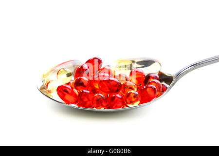 Colored capsules with vitamins in a spoonful.