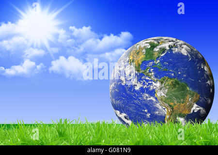 blue planet Earth on green grass and blue sky back Stock Photo